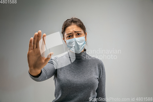 Image of Caucasian woman wearing the respiratory protection mask against air pollution and dusk on grey studio background