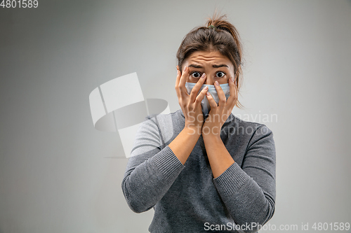 Image of Caucasian woman wearing the respiratory protection mask against air pollution and dusk on grey studio background