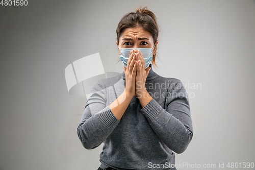 Image of Caucasian woman wearing the respiratory protection mask against air pollution and dusk on grey studio background