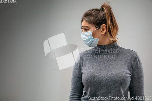 Image of Caucasian woman wearing the respiratory protection mask against air pollution and dusk on grey studio background