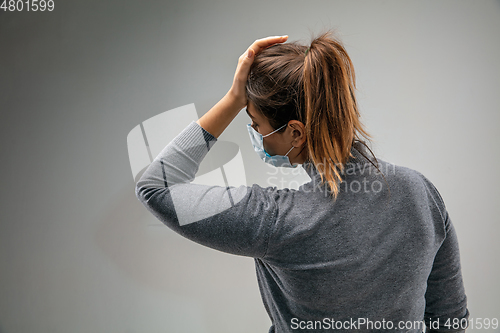 Image of Caucasian woman wearing the respiratory protection mask against air pollution and dusk on grey studio background