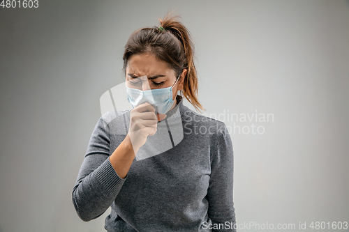 Image of Caucasian woman wearing the respiratory protection mask against air pollution and dusk on grey studio background