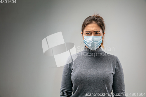 Image of Caucasian woman wearing the respiratory protection mask against air pollution and dusk on grey studio background