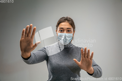 Image of Caucasian woman wearing the respiratory protection mask against air pollution and dusk on grey studio background