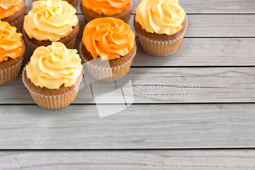 Image of cupcakes with frosting on wooden boards background