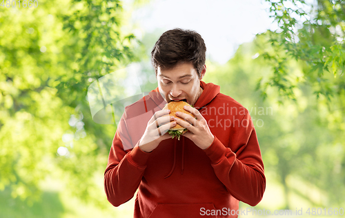 Image of hungry young man eating hamburger