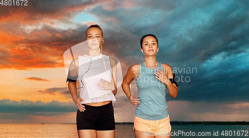 Image of young women with earphones and smartphones running