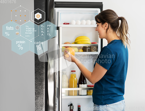 Image of happy woman taking food from fridge at home