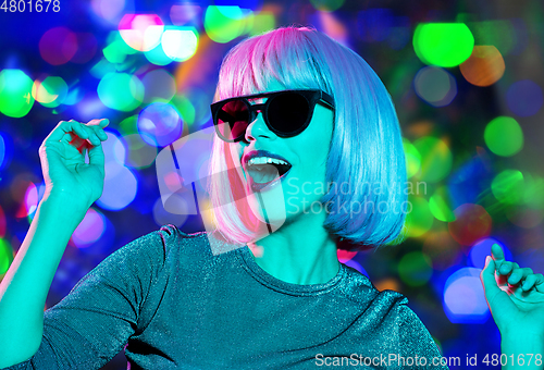 Image of happy woman in pink wig and sunglasses dancing