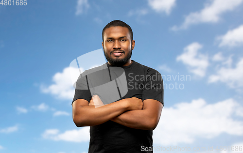 Image of african american man with crossed arms over sky