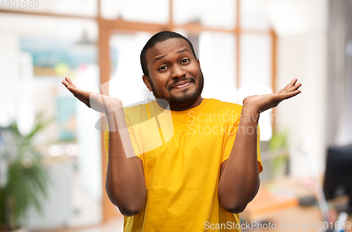 Image of african american man in yellow t-shirt shrugging
