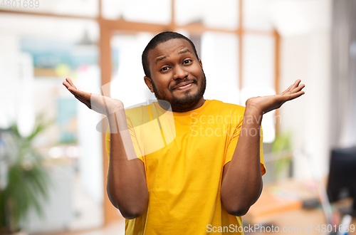 Image of african american man in yellow t-shirt shrugging
