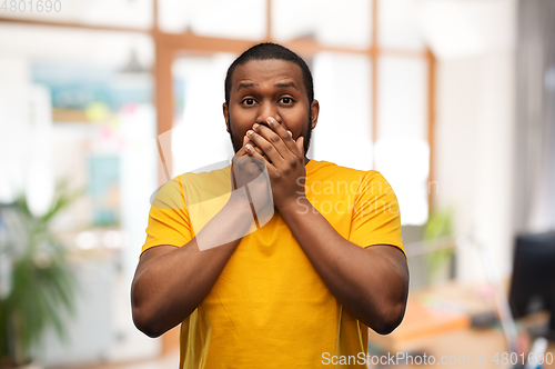 Image of scared african american man covering his mouth