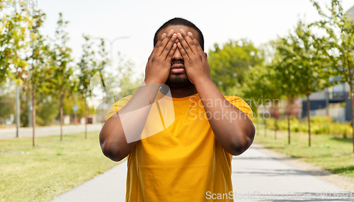 Image of african american man closing his eyes by hands