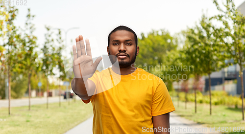 Image of african american man showing stop gesture outdoors