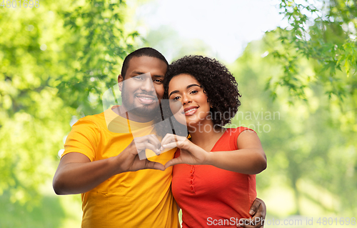 Image of happy african american couple making hand heart