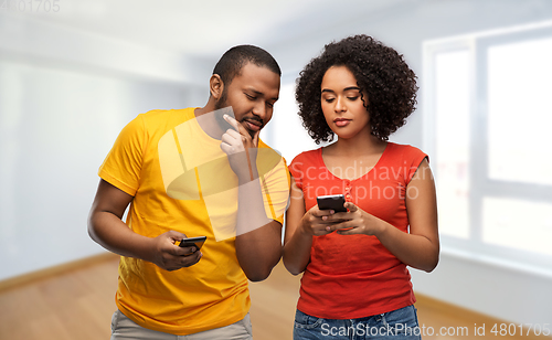 Image of happy african american couple with smartphones