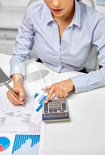 Image of businesswoman with papers and calculator at office