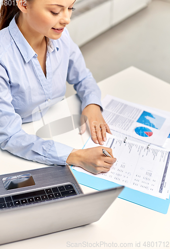 Image of businesswoman with papers working at office