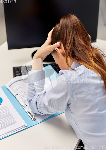 Image of stressed businesswoman with papers at office