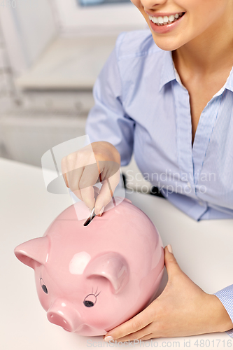 Image of businesswoman with piggy bank and coin at office