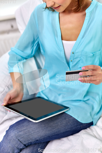 Image of happy woman with tablet pc and credit card at home