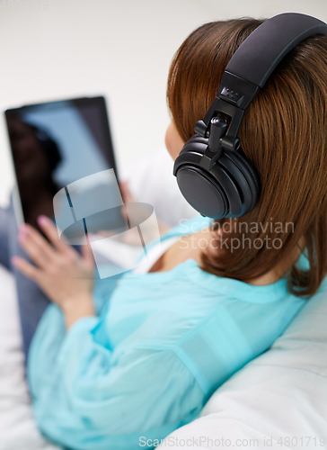 Image of woman with tablet pc and headphones at home