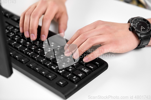 Image of male hands typing on computer keyboard on table