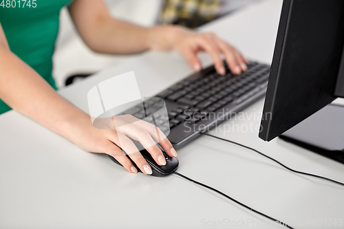 Image of female hand with computer mouse on table