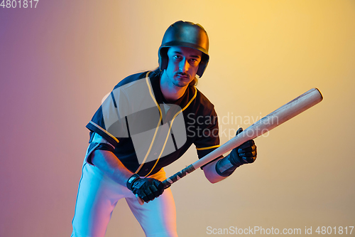 Image of Baseball player, pitcher in a black uniform practicing on gradient background in neon light