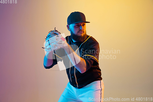 Image of Baseball player, pitcher in a black uniform practicing on gradient background in neon light