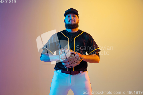 Image of Baseball player, pitcher in a black uniform practicing on gradient background in neon light