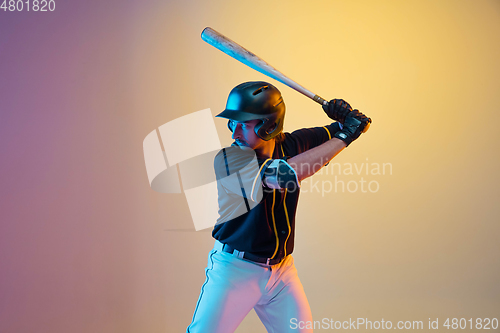 Image of Baseball player, pitcher in a black uniform practicing on gradient background in neon light