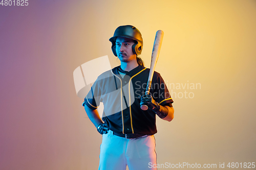 Image of Baseball player, pitcher in a black uniform practicing on gradient background in neon light