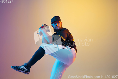 Image of Baseball player, pitcher in a black uniform practicing on gradient background in neon light