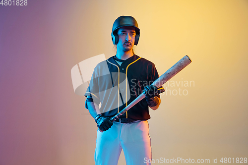 Image of Baseball player, pitcher in a black uniform practicing on gradient background in neon light