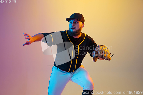 Image of Baseball player, pitcher in a black uniform practicing on gradient background in neon light