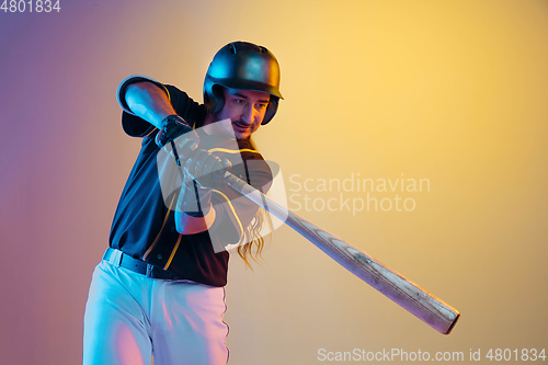 Image of Baseball player, pitcher in a black uniform practicing on gradient background in neon light