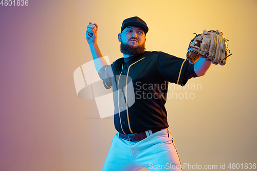 Image of Baseball player, pitcher in a black uniform practicing on gradient background in neon light