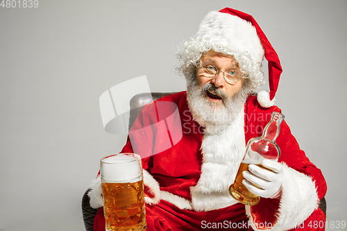 Image of Santa Claus drinking beer sitting on armchair, congratulating of New Year 2020