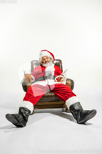 Image of Santa Claus drinking beer sitting on armchair, congratulating of New Year 2020