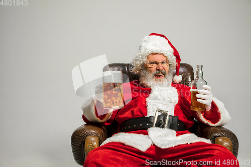 Image of Santa Claus drinking beer sitting on armchair, congratulating of New Year 2020