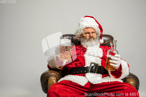 Image of Santa Claus drinking beer sitting on armchair, congratulating of New Year 2020