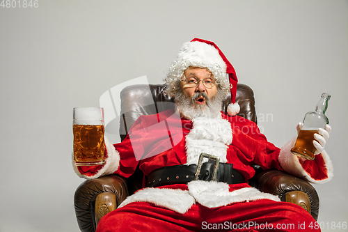 Image of Santa Claus drinking beer sitting on armchair, congratulating of New Year 2020