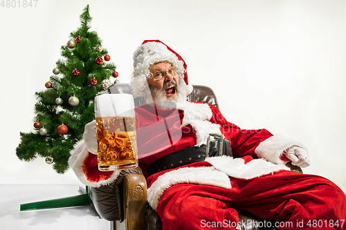 Image of Santa Claus drinking beer near Christmas tree, congratulating of