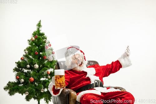 Image of Santa Claus drinking beer near Christmas tree, congratulating of