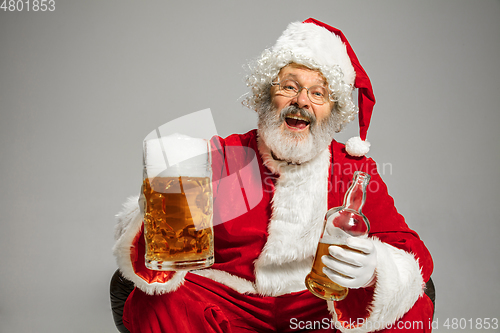 Image of Santa Claus drinking beer sitting on armchair, congratulating of New Year 2020