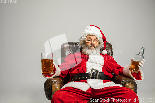 Image of Santa Claus drinking beer sitting on armchair, congratulating of New Year 2020