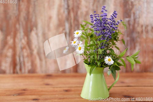 Image of bunch of herbs and flowers in green jug on table