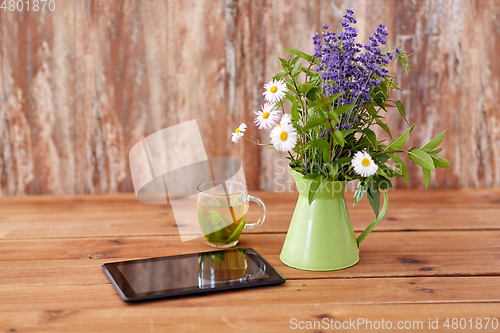 Image of tablet computer, herbal tea and flowers in jug